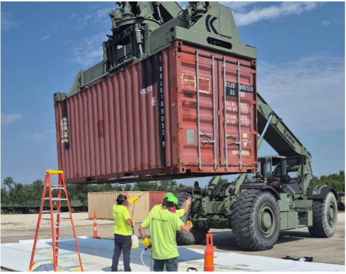 Military crane lifts shipping container above Wellington technicians