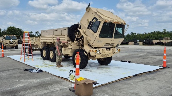 Military cargo truck tilted during maintenance on tarp